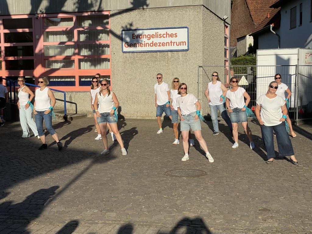 Tanzgruppe in weißen Oberteilen und Jeans vor dem Evangelischen Gemeindezentrum
